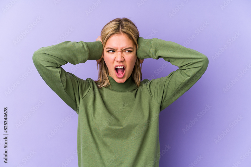 Young blonde caucasian woman isolated covering ears with hands trying not to hear too loud sound. Young blonde caucasian woman isolated covering ears with hands trying not to hear too loud sound.