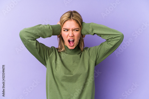 Young blonde caucasian woman isolated covering ears with hands trying not to hear too loud sound. © Asier
