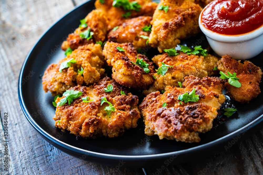 Fried chicken nuggets with ketchup on wooden table Fried chicken nuggets with ketchup on wooden table