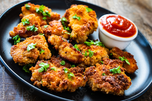 Fried chicken nuggets with ketchup on wooden table