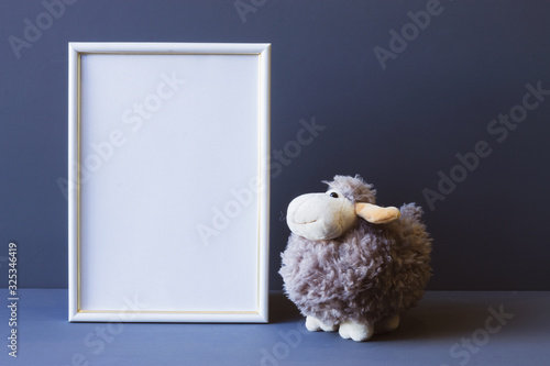 white photo frame and soft toy on a gray background copy space