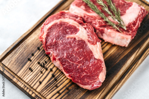 Raw meat beef steak, with ingredients for cooking on a wooden board and white background. Top view