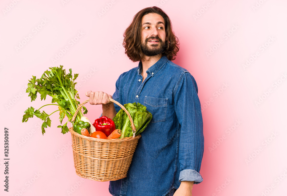Young man picking organic vegetables from his garden isolated looks aside smiling, cheerful and pleasant. Young man picking organic vegetables from his garden isolated looks aside smiling, cheerful and pleasant.