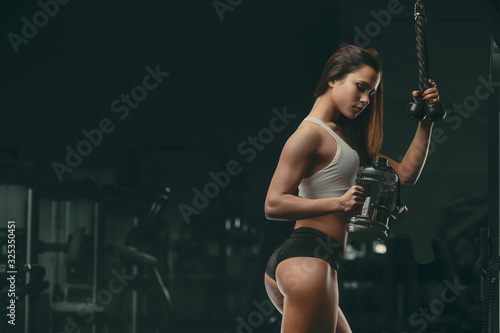 Fitness woman drinking water at workout in the gym