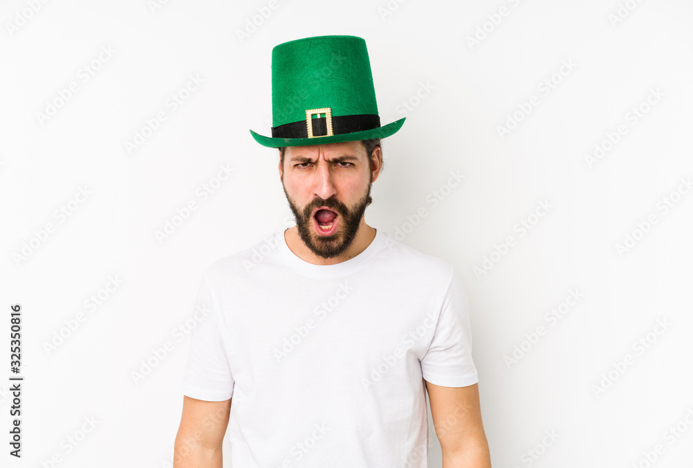 Young caucasian man wearing a saint patricks hat isolated screaming very angry and aggressive. Young caucasian man wearing a saint patricks hat isolated screaming very angry and aggressive.