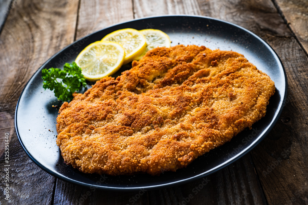 Schnitzel with lemon on timber background Schnitzel with lemon on timber background