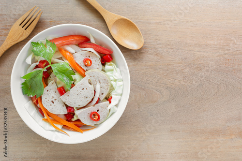 top view  of spicy vietnamese pork sausage salad in a ceramic bowl on wooden table. delicious asian style food menu. photo