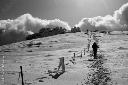 Fotografia backlit hiker in the distance ascending next to a fence a snowy mountain in blac