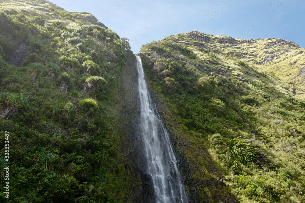 waterfall on cliff side with sky and vegetation