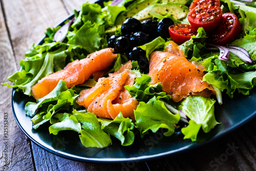 Salmon salad - smoked salmon and vegetables on black stone background