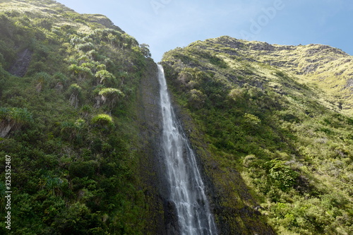 waterfall on cliff side with sky and vegetation