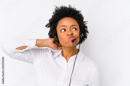 Young african american telemarketer woman isolated touching back of head, thinking and making a choice. photo