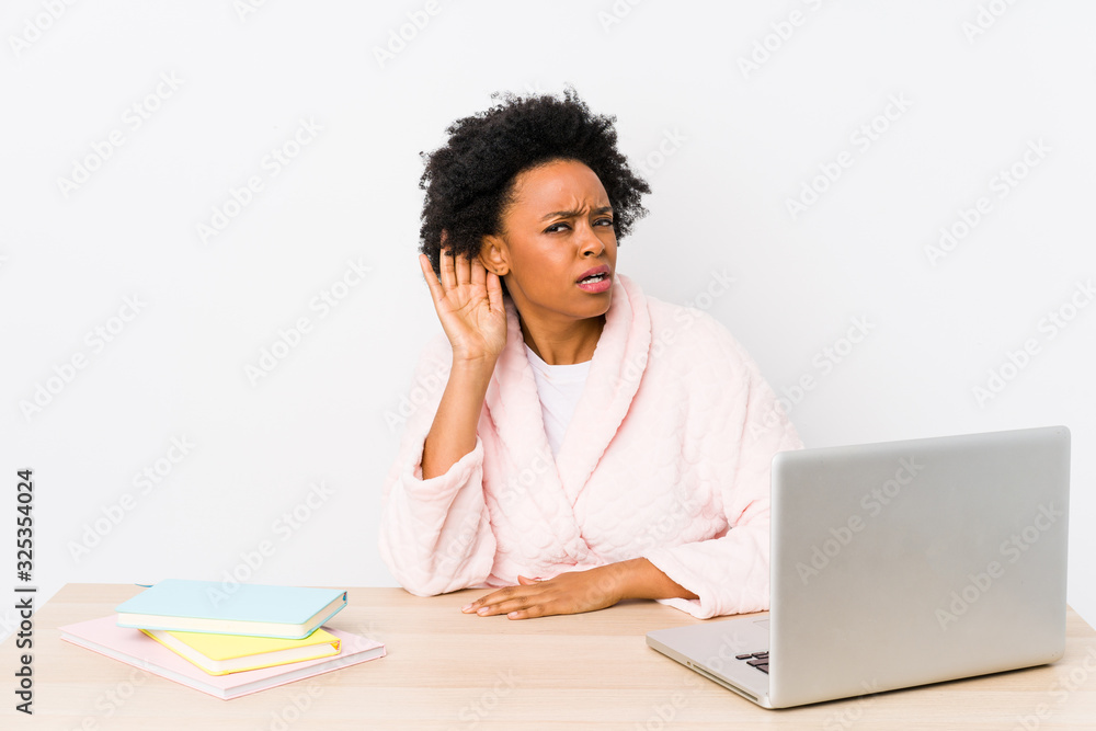Middle aged african american woman working at home isolated trying to listening a gossip. Middle aged african american woman working at home isolated trying to listening a gossip.