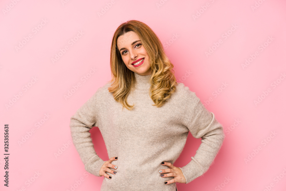 Young blonde cute woman wearing a sweater isolated confident keeping hands on hips. Young blonde cute woman wearing a sweater isolated confident keeping hands on hips.