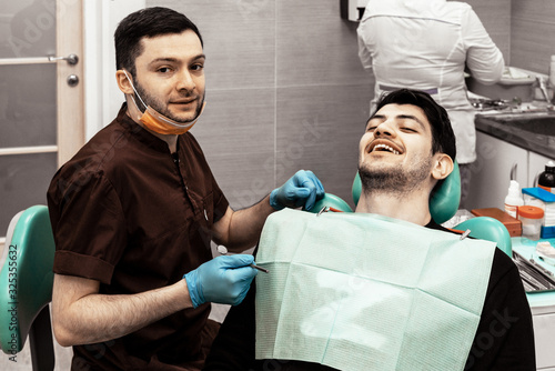A young dentist discusses a diagnosis and treatment plan with a patient. Discussion and demonstration of treatment results. Health care  aesthetic medicine.