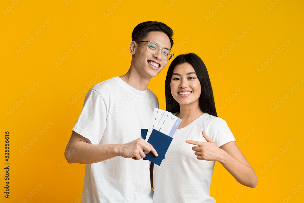 Happy young asian couple holding passports and tickets Happy young asian couple holding passports and tickets