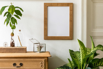Minimalistic compositon with wooden vintage commode, brown mock up photo frame, avocado plant, plant and elegant personal accessories. Stylish retro living room. White walls. Home decor. Template. 