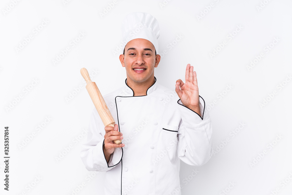 Young latin chef man isolated cheerful and confident showing ok gesture. Young latin chef man isolated cheerful and confident showing ok gesture.