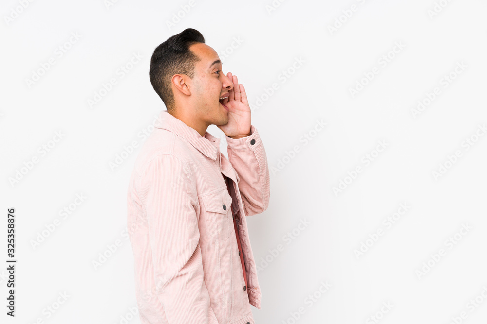 Young latin man posing isolated shouting and holding palm near opened mouth. Young latin man posing isolated shouting and holding palm near opened mouth.