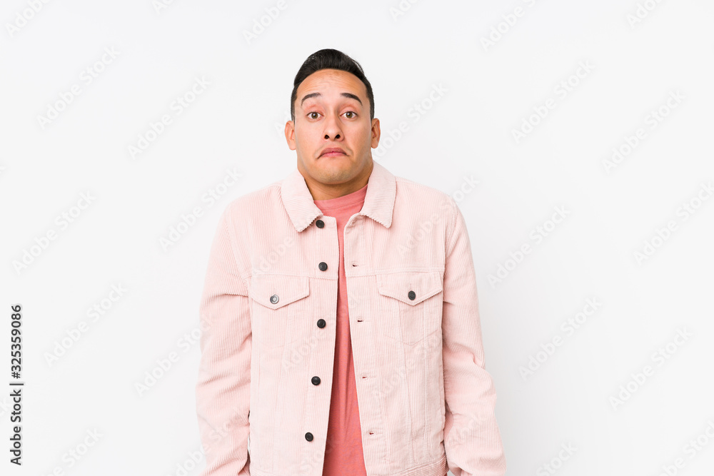 Young latin man posing isolated shrugs shoulders and open eyes confused. Young latin man posing isolated shrugs shoulders and open eyes confused.