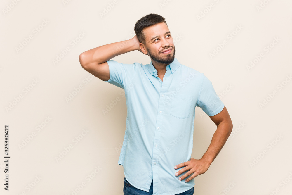 Young south-asian man touching back of head, thinking and making a choice. Young south-asian man touching back of head, thinking and making a choice.