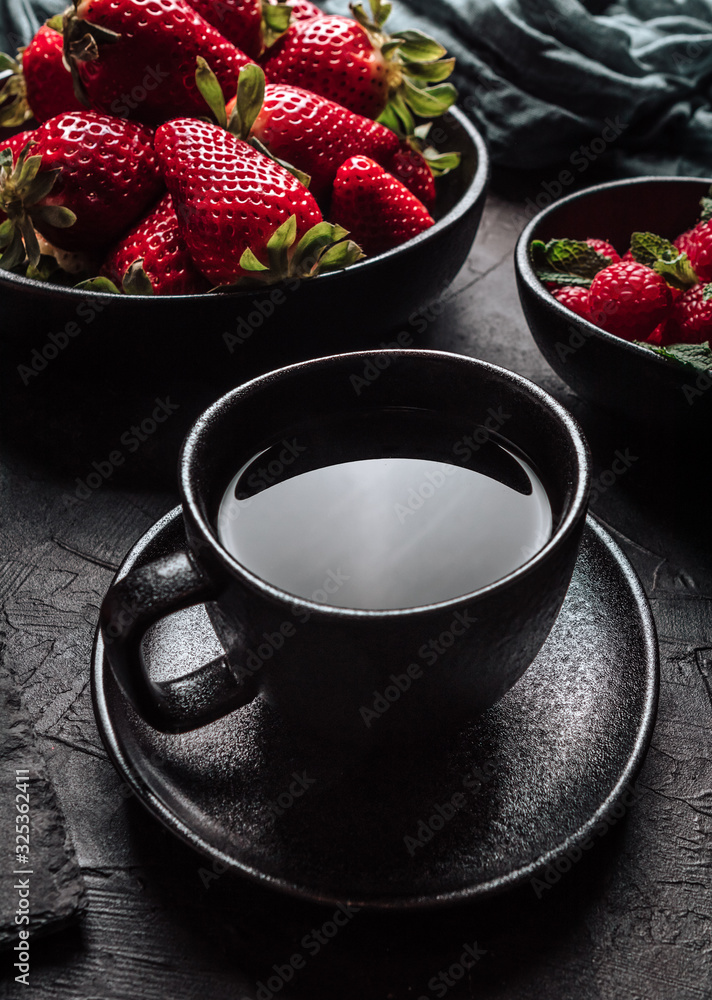 Still life with a bowl of strawberries, a bowl of raspberries, a cutting board and a cup of tea Still life with a bowl of strawberries, a bowl of raspberries, a cutting board and a cup of tea