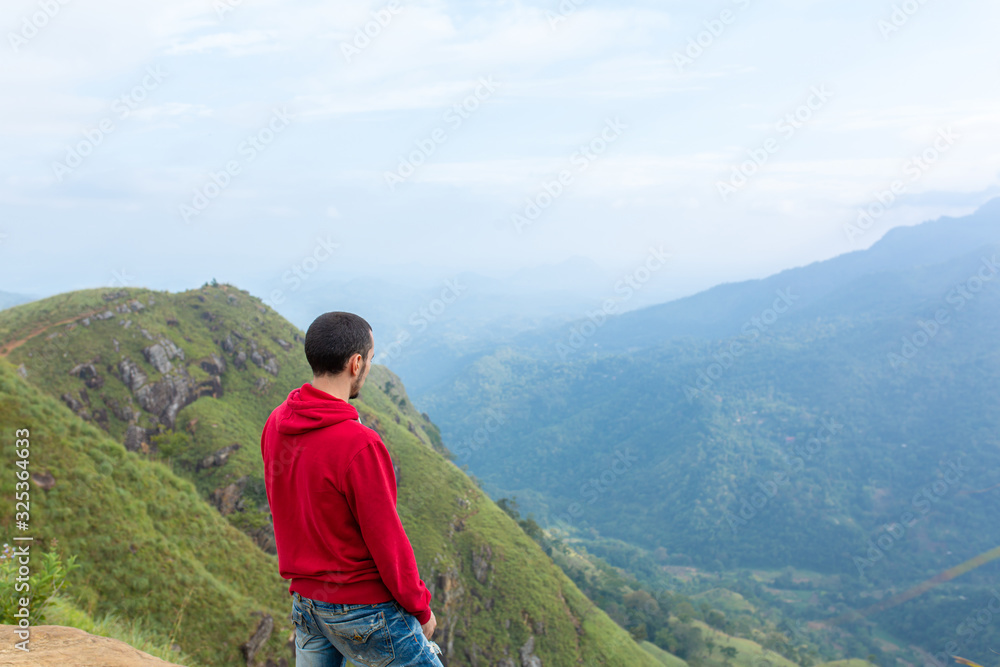 A man enjoying the mountain scenery on the edge of a cliff