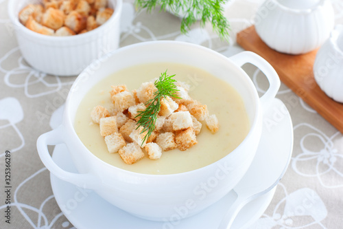 Mashed potato soup with homemade croutons in a white soup plate, horizontal