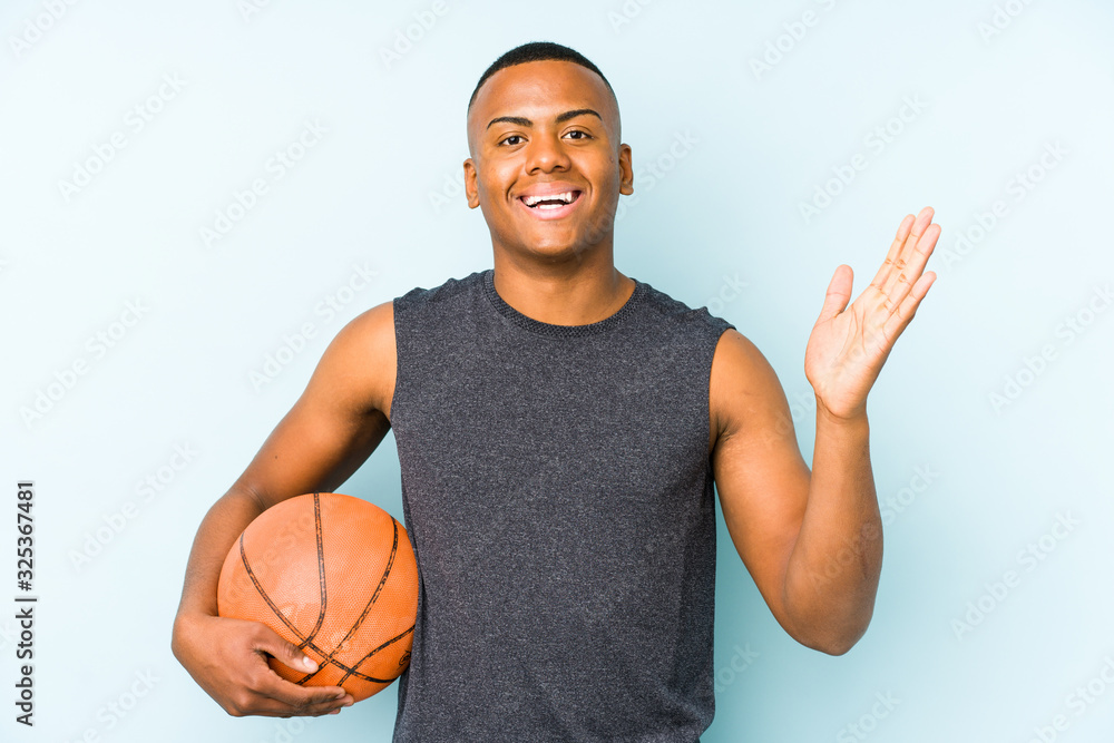 Young colombian man playing basketball isolated receiving a pleasant surprise, excited and raising hands. Young colombian man playing basketball isolated receiving a pleasant surprise, excited and raising hands.