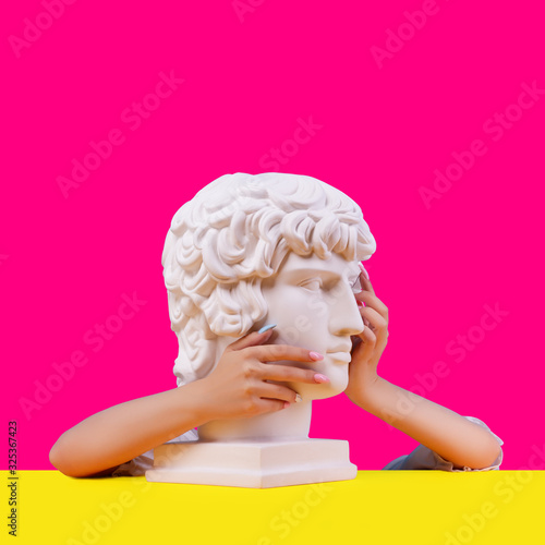 Gypsum statue of Antinous head. Creative. Plaster statue of Aphrodite's head in women hends  . On a abstract background.
