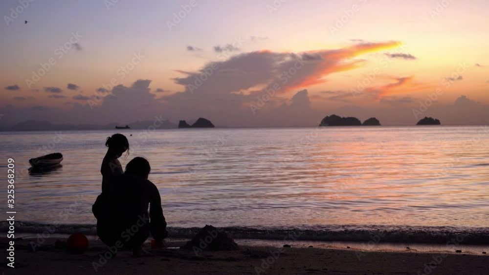 Mom with daughter play in the sand on the beach. Sunset. Beach ocean. Silhouettes of people. Build a sand castle. Mom with daughter play in the sand on the beach. Sunset. Beach ocean. Silhouettes of people. Build a sand castle.