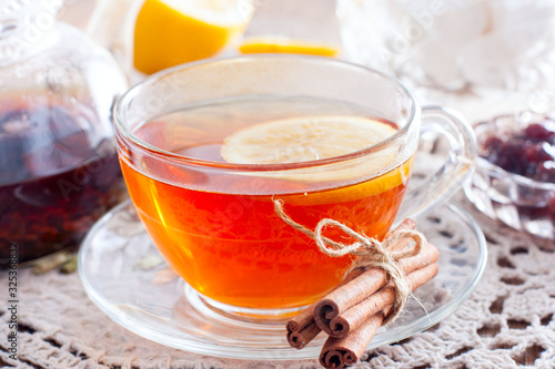 Black tea with cinnamon and lemon in a glass cup on a wooden table, horizontal