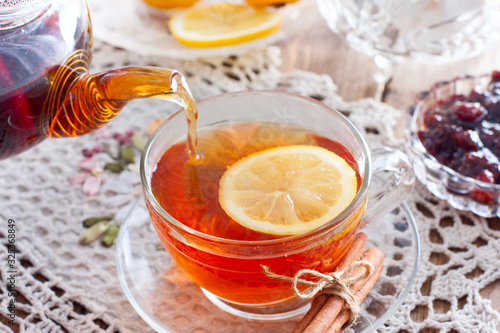 Black tea with cinnamon and lemon in a glass cup on a wooden table, horizontal