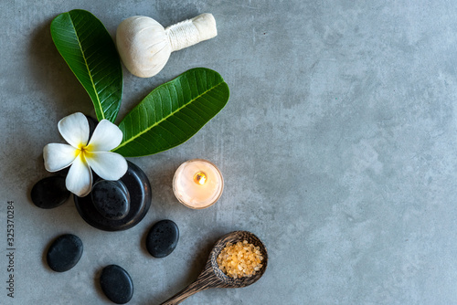 Thai Spa. Top view of white Plumeria flower setting for massage treatment and relax on black blackboard for text banner and copy space. Spa flower with black stones pile for body therapy. 