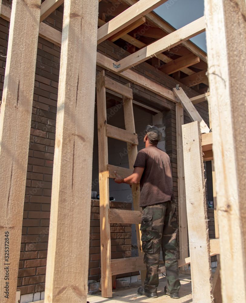 A worker measures a wooden workpiece with a meter. A worker measures a wooden workpiece with a meter.