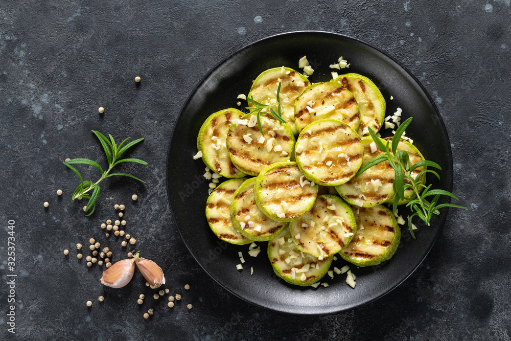 Grilled zucchini, courgette with garlic and rosemary on plate, top view Grilled zucchini, courgette with garlic and rosemary on plate, top view