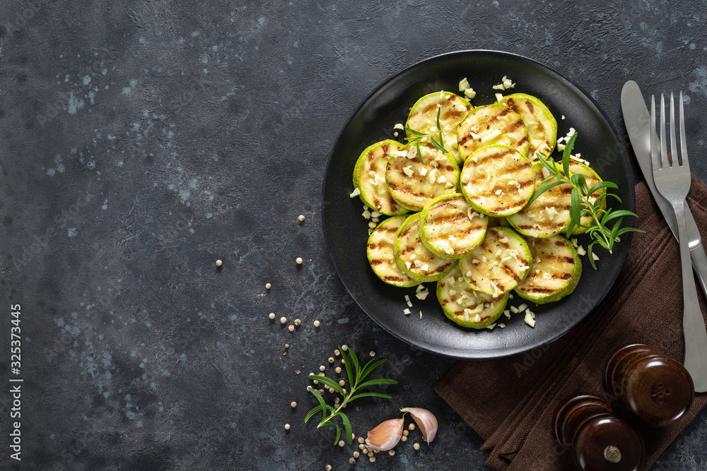 Grilled zucchini, courgette with garlic and rosemary on plate, top view Grilled zucchini, courgette with garlic and rosemary on plate, top view