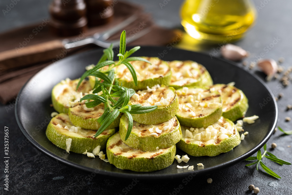 Grilled zucchini, courgette with garlic and rosemary on plate Grilled zucchini, courgette with garlic and rosemary on plate