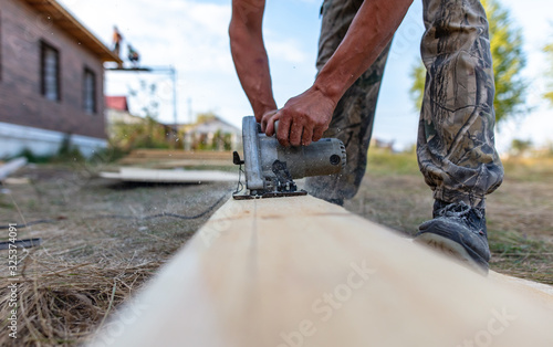 A worker saws a wooden beam.