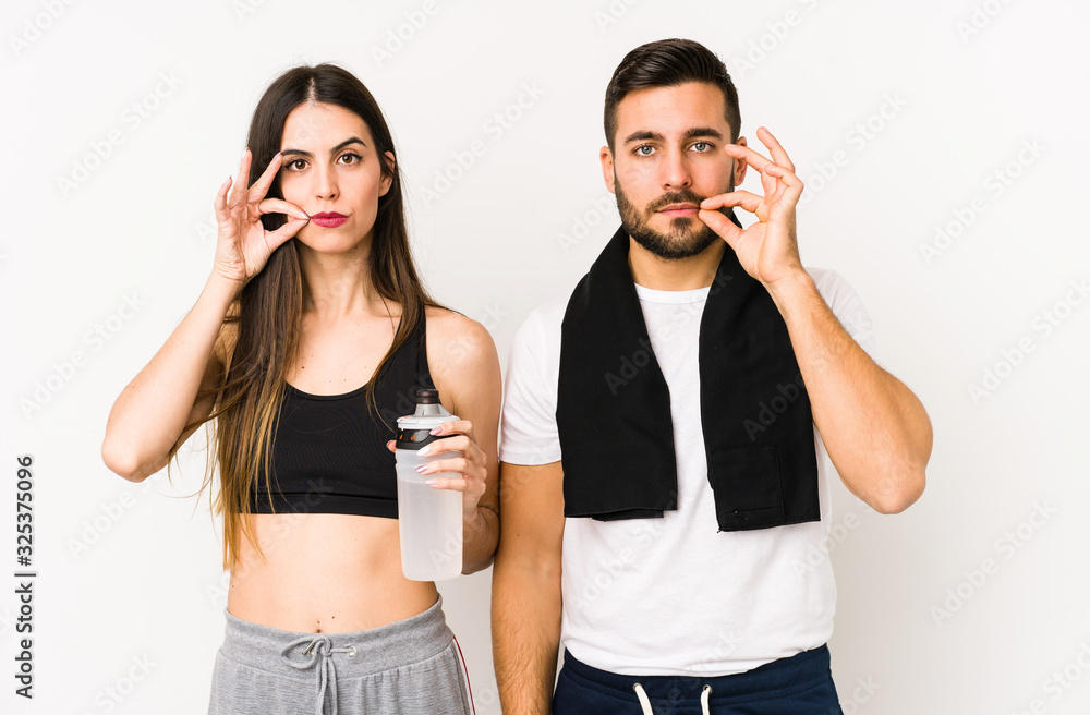 Young caucasian fitness couple isolated with fingers on lips keeping a secret. Young caucasian fitness couple isolated with fingers on lips keeping a secret.
