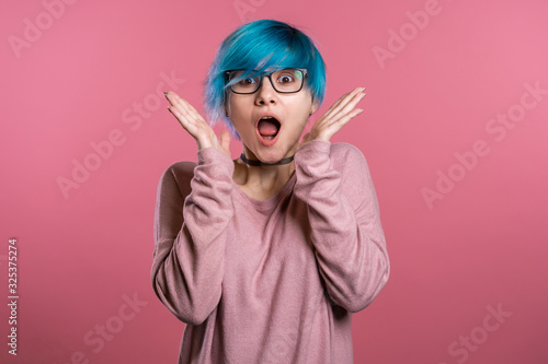 Pretty female shocked model with colorful hairstyle on pink background. OMG  wow effect. Girl with delight. Surprised excited happy woman