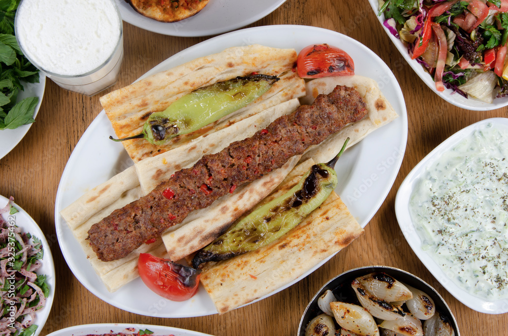 Traditional Turkish Adana kebab or kebap meat food, appetizers, ayran and salgam on table from top view in turkish restaurant. Traditional Turkish Adana kebab or kebap meat food, appetizers, ayran and salgam on table from top view in turkish restaurant.