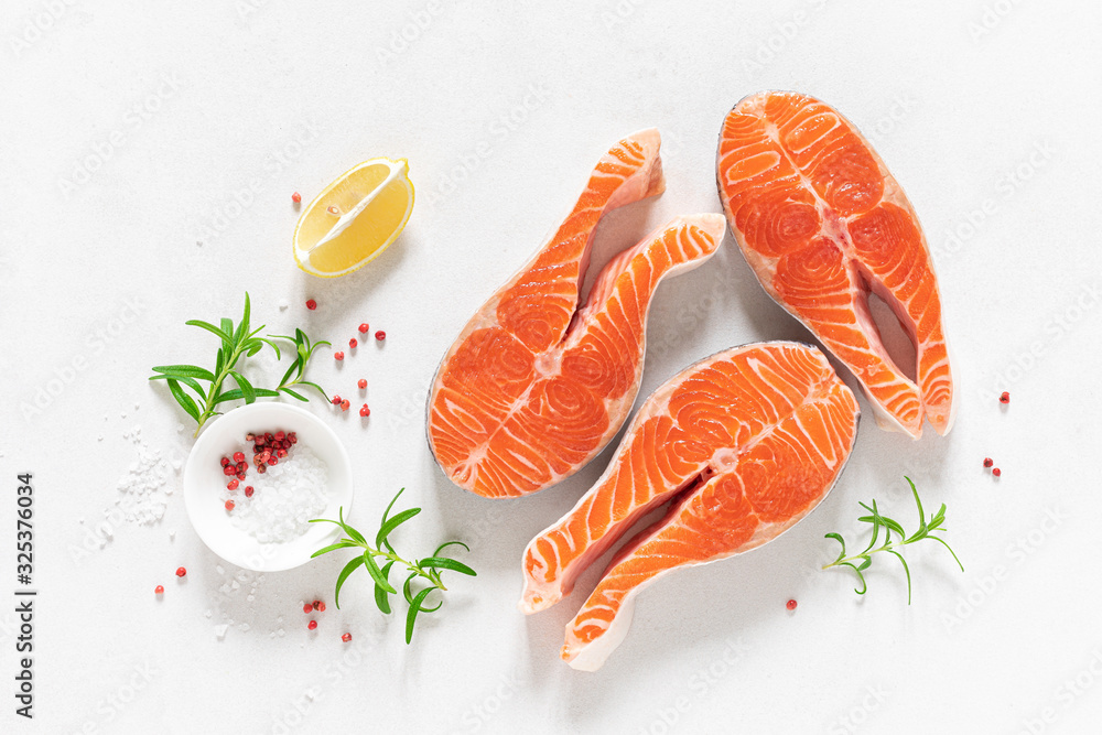 Salmon. Fresh raw salmon fish steaks with cooking ingredients, herbs and lemon on white background, top view Salmon. Fresh raw salmon fish steaks with cooking ingredients, herbs and lemon on white background, top view