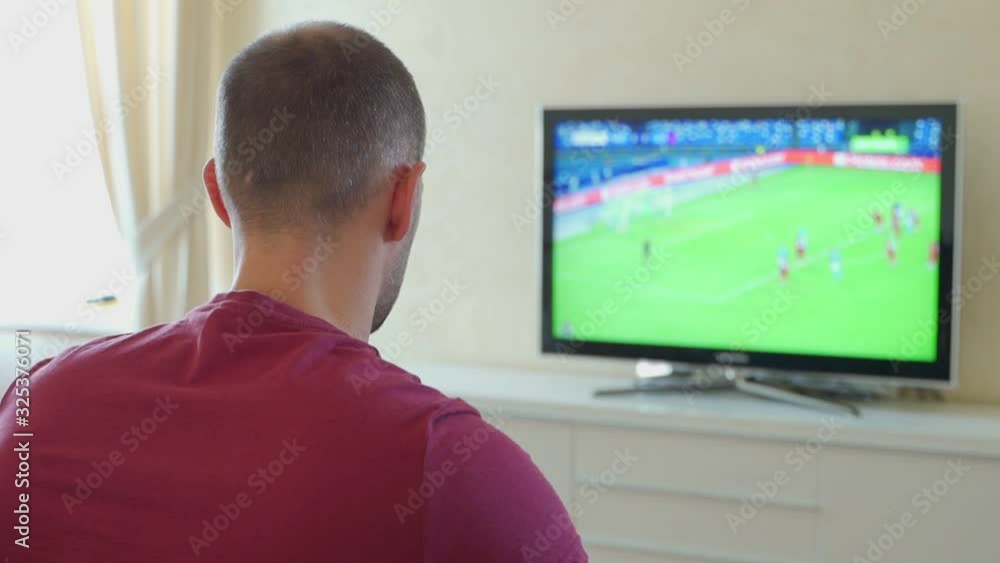 Nervous man watching game on television, happy with result, back view Nervous man watching game on television, happy with result, back view
