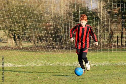 Young boy kicking a soccer ball.