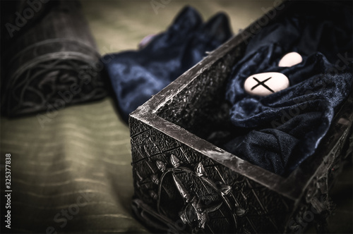 Closeup of occult mystic rune stones on blue velor silk in an occult box for a pagan psychic destiny reading ritual - Concept of supernatural, witchcraft, destiny and mystical fortune-telling photo