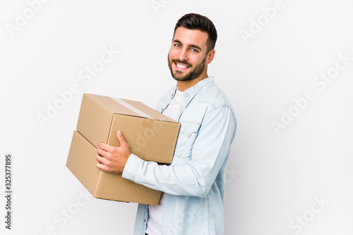 Young caucasian man moving to a new home isolated looks aside smiling, cheerful and pleasant.
