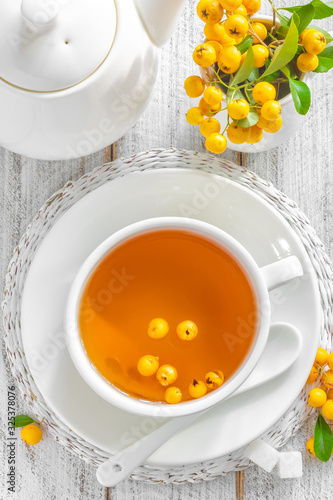Hawthorn tea in a cup with fresh berries on white wooden table, healthy herbal healing hot drink