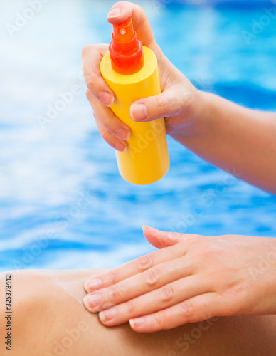 Woman applying sunblock cream on her legs.