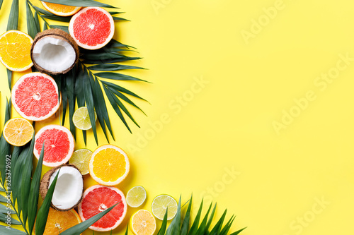 Summer vibes. Composition with exotic fruits on bright yellow background. Summertime vacation, cocktail, tropical beach. Creative fruity layout, copy space